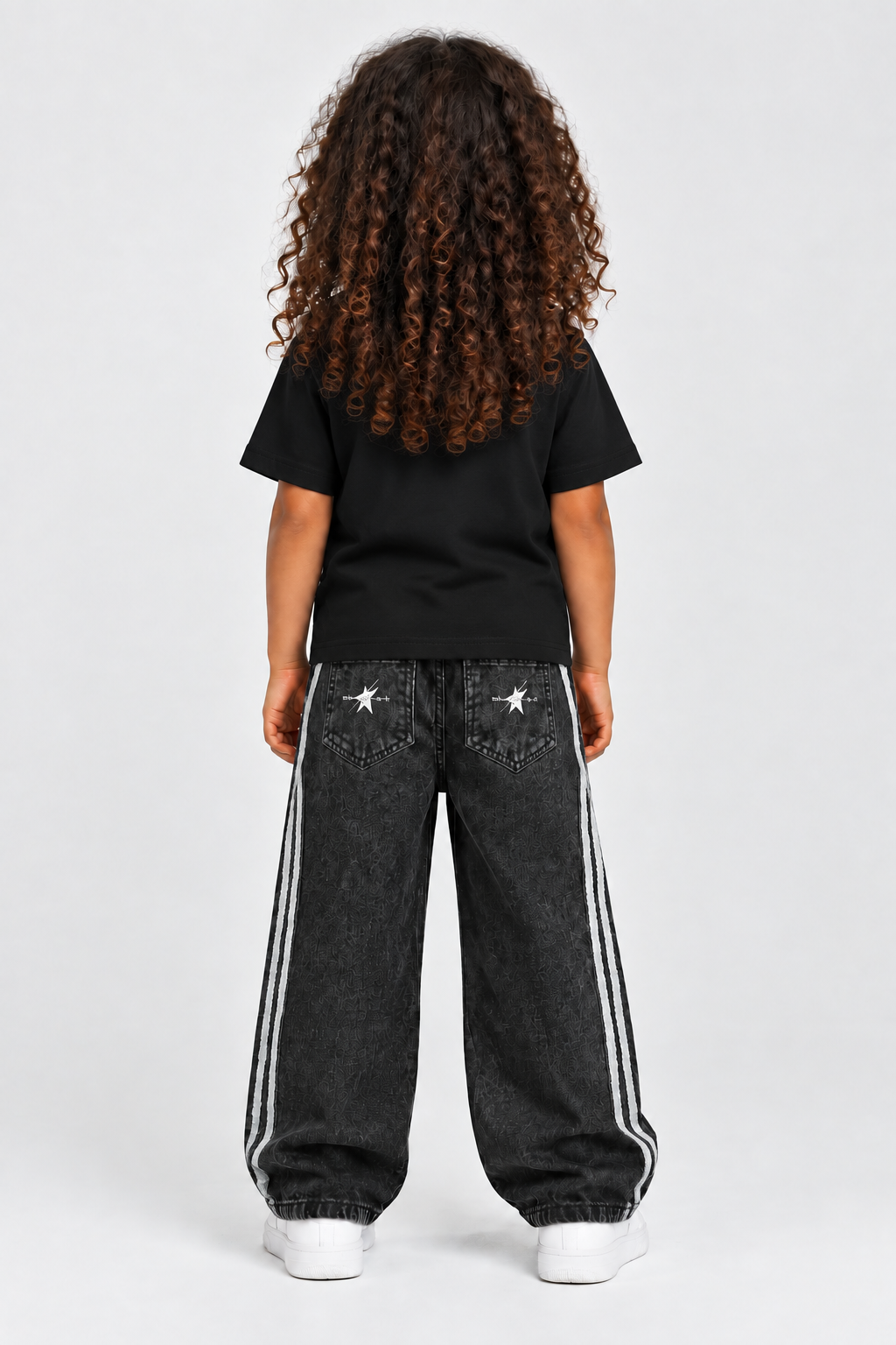 Child model wearing the black STOLD tee and striped jeans, back view