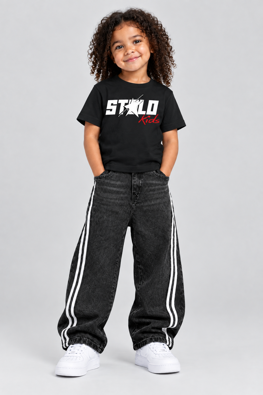Same child model wearing the black STOLD Kids tee and striped jeans, front view