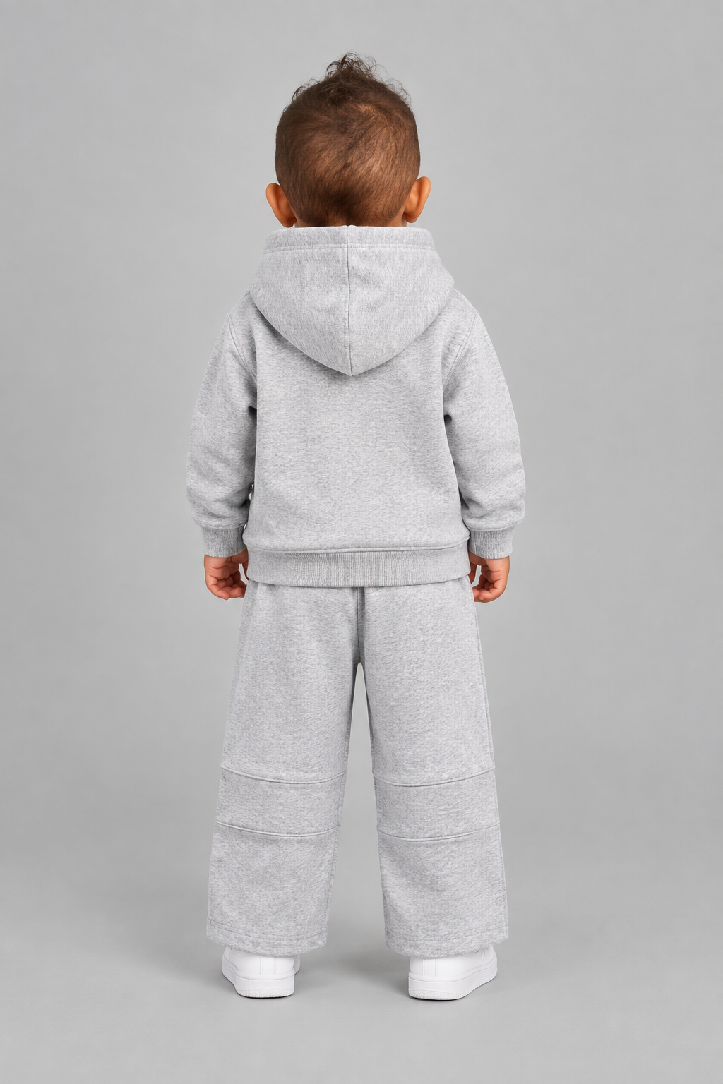 Same toddler model in the light-grey STOLD Kids hoodie and pants set, back view