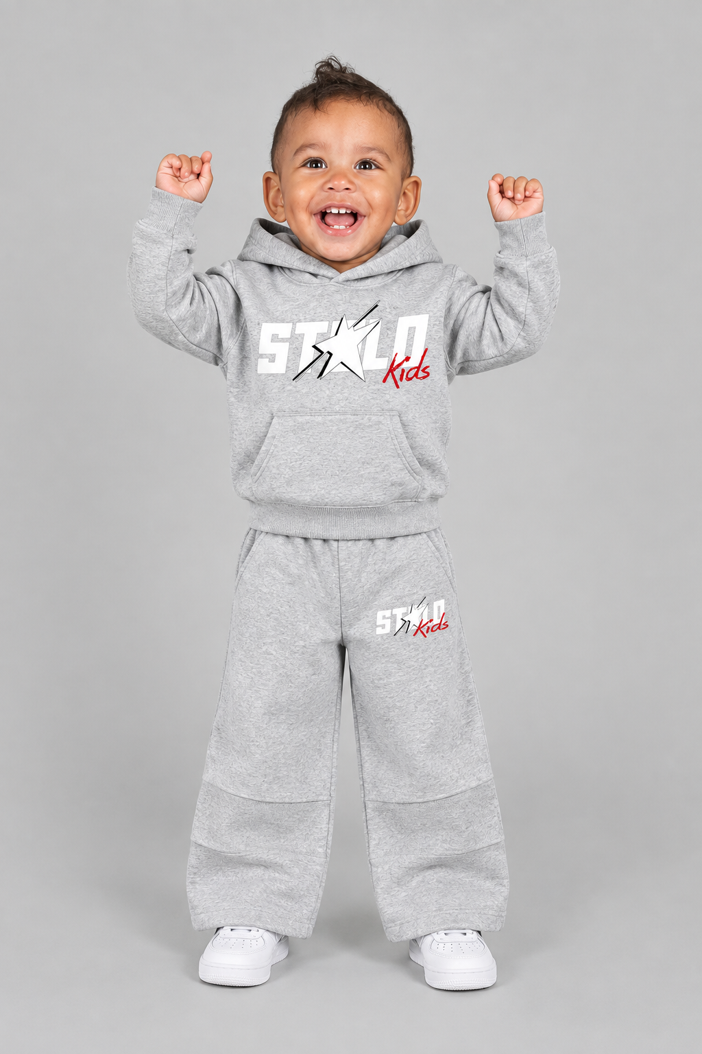 Same toddler model in the light-grey STOLD Kids hoodie and pants set, front view